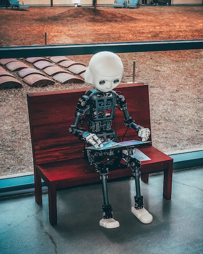 A robot sitting on a bench with a laptop giving a visual representation of AI driven content creation. 