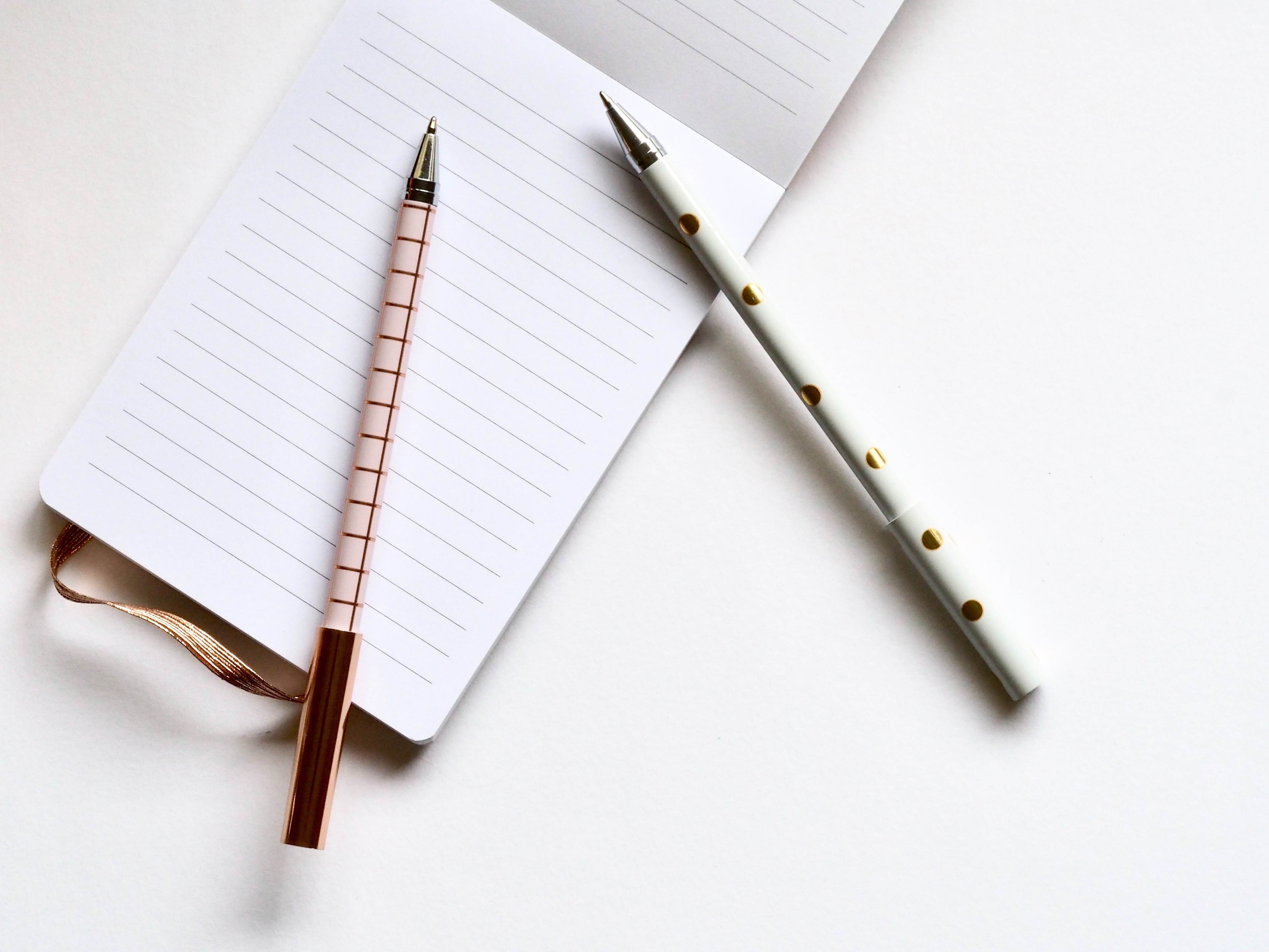 Two pens and notebook for jotting HVAC blog post ideas on a white surface.