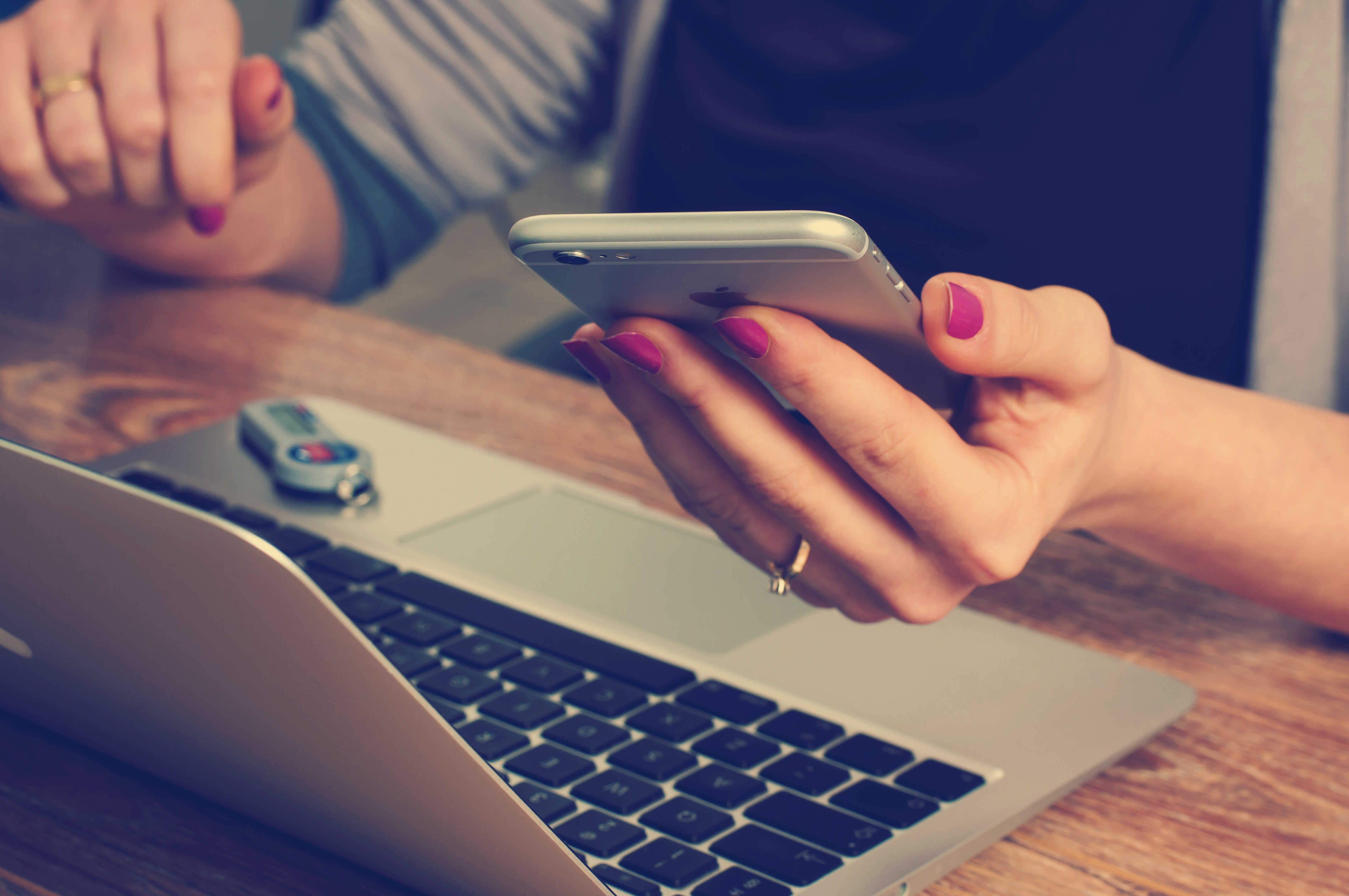 Woman writing SEO optimized articles for landscaping business website on laptop and cell phone.'